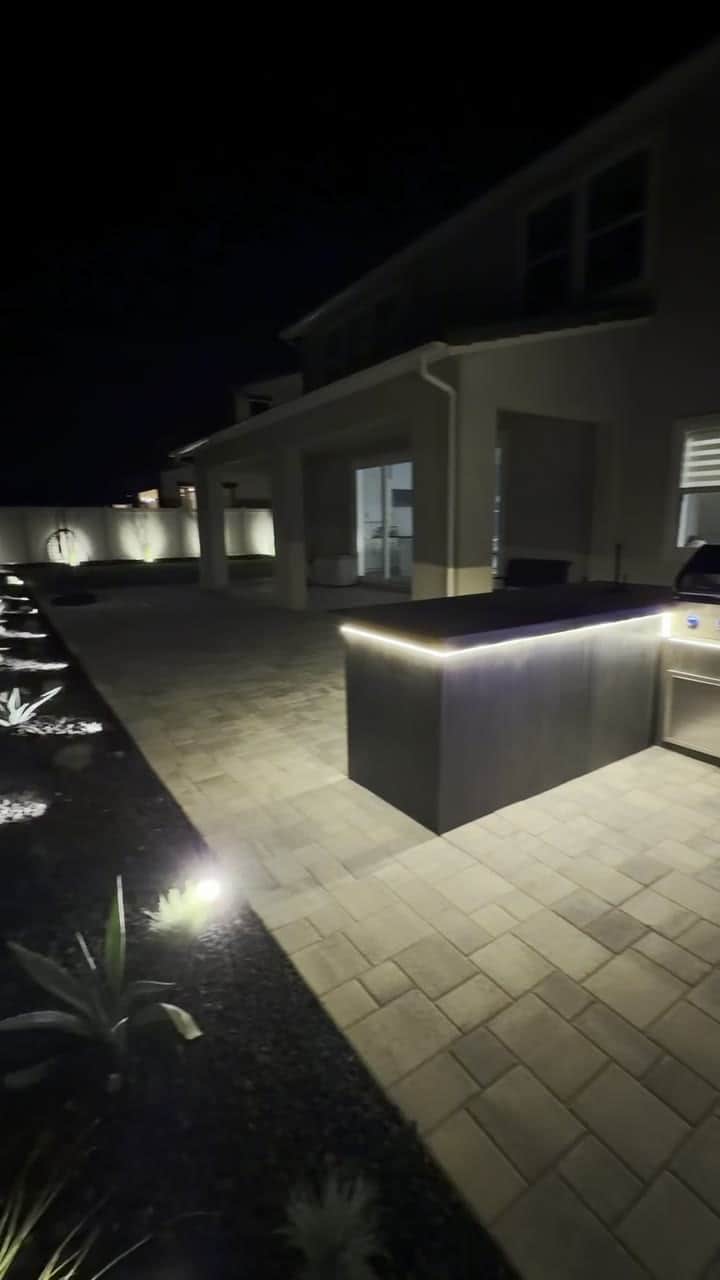 Low-voltage landscape lighting installed by Five Stars Builders glowing across a Southern California backyard at night